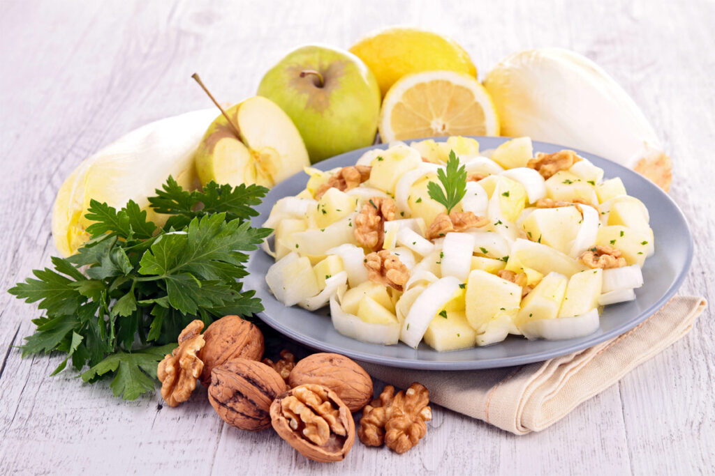 Chicorée-Salat mit Walnüssen und Apfel auf einem Teller.
