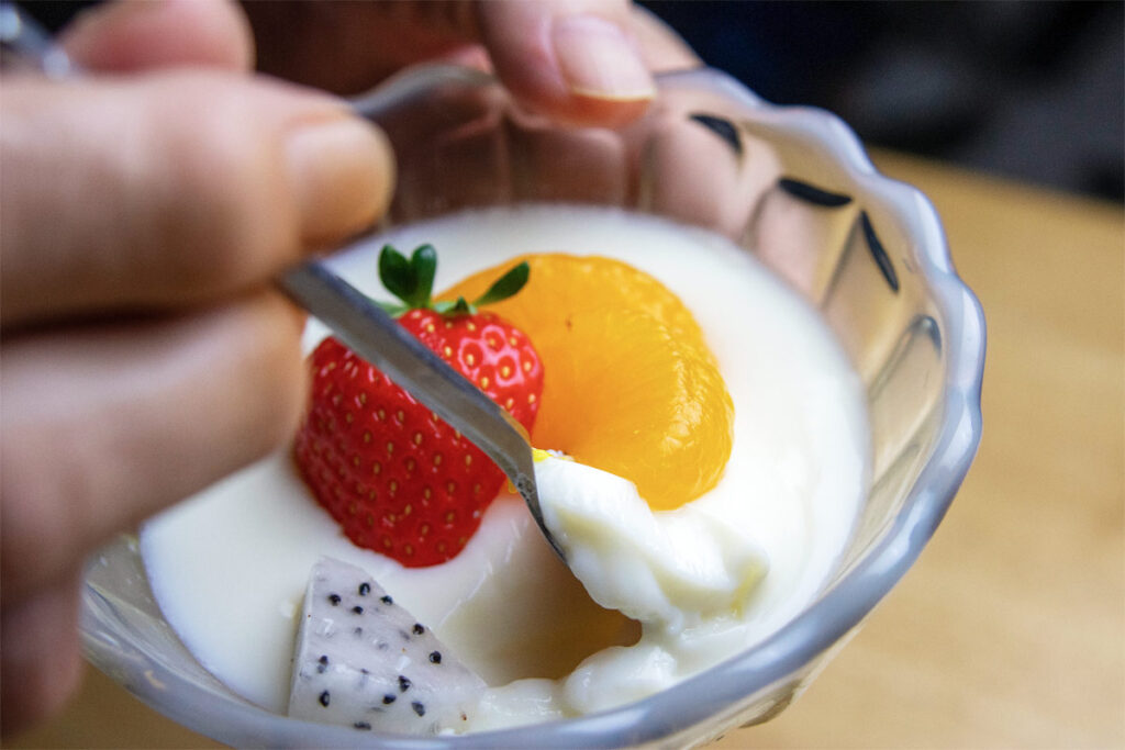 Frau isst japanischen Milchpudding mit Löffel