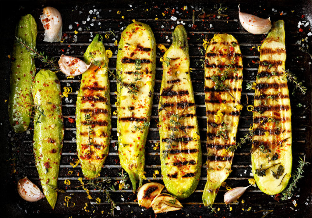 gegrillte Zucchini auf einem Rost mit Knoblauchzehen