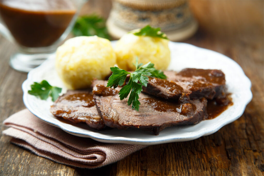 Rinderbraten mit Kartoffelklößen auf einem Teller.