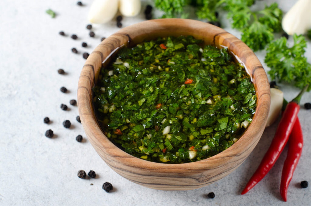 Traditionelle argentinische Chimichurri Sauce aus Petersilie, Koriander, Knoblauch und Chili-Pfeffer in einer Holzschale.