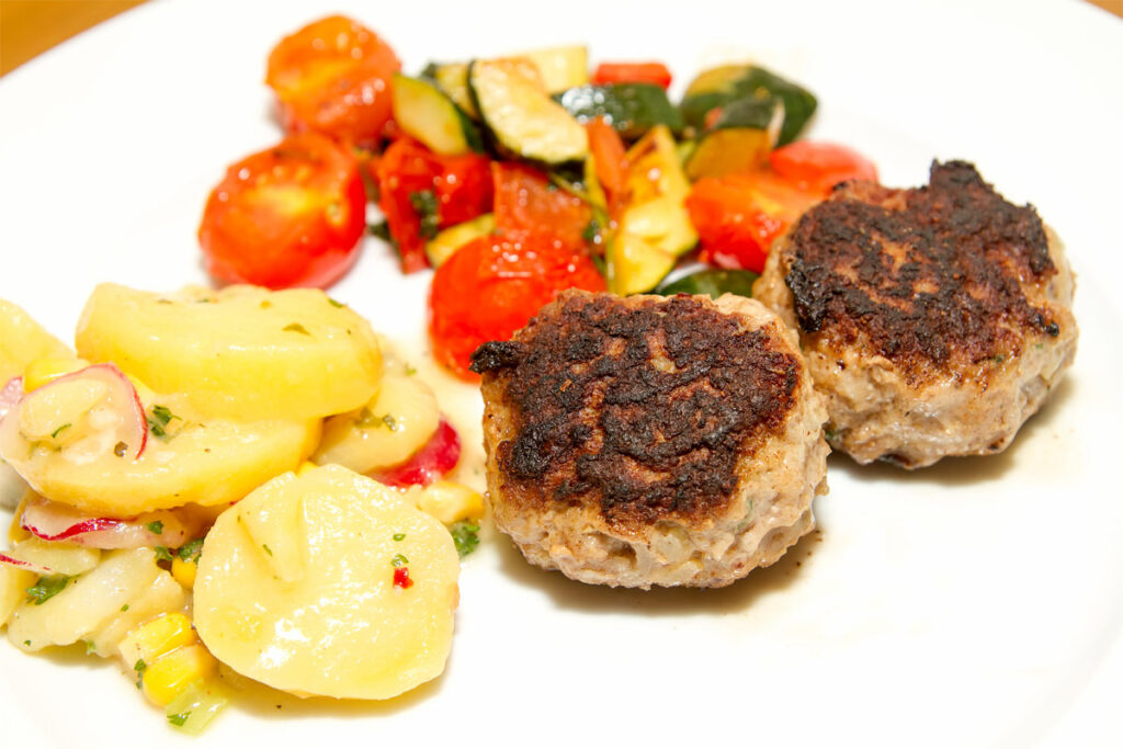 Zwei Frikadellen auf einem Teller mit Kartoffelsalat
