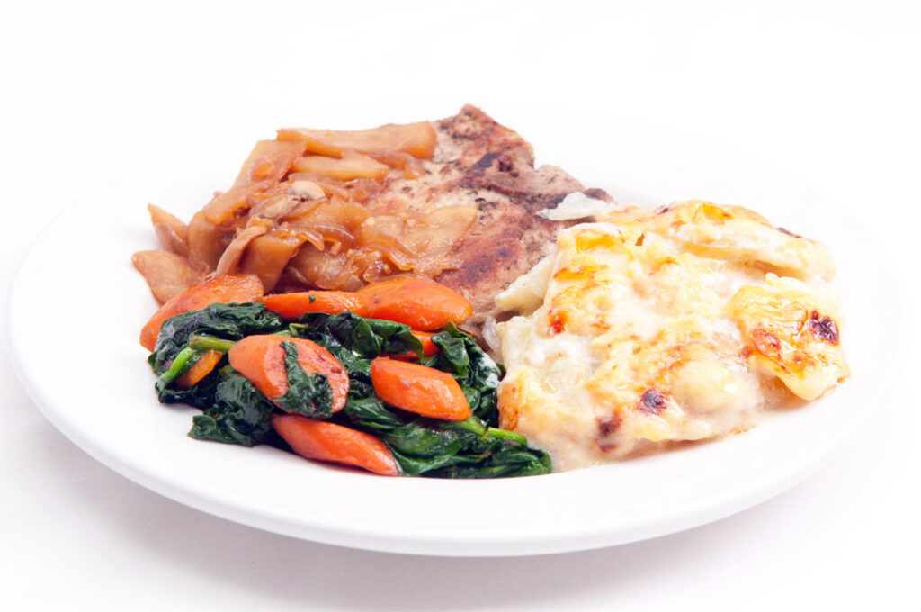 Teller mit Schweinekotelett mit Kartoffelgratin und Gemüse