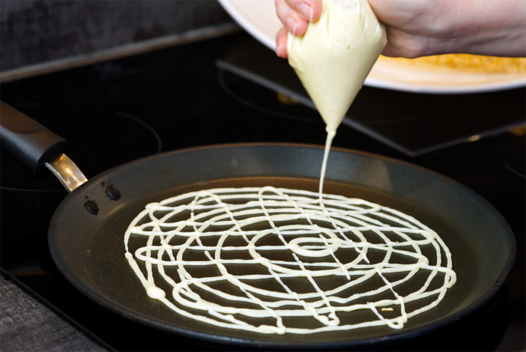 Frau bäckt Waffeln in einer Pfanne