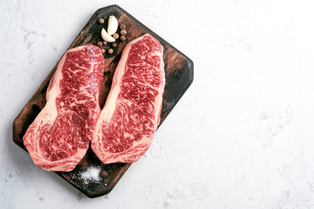 zwei Strip Steaks auf einem Holzbrett