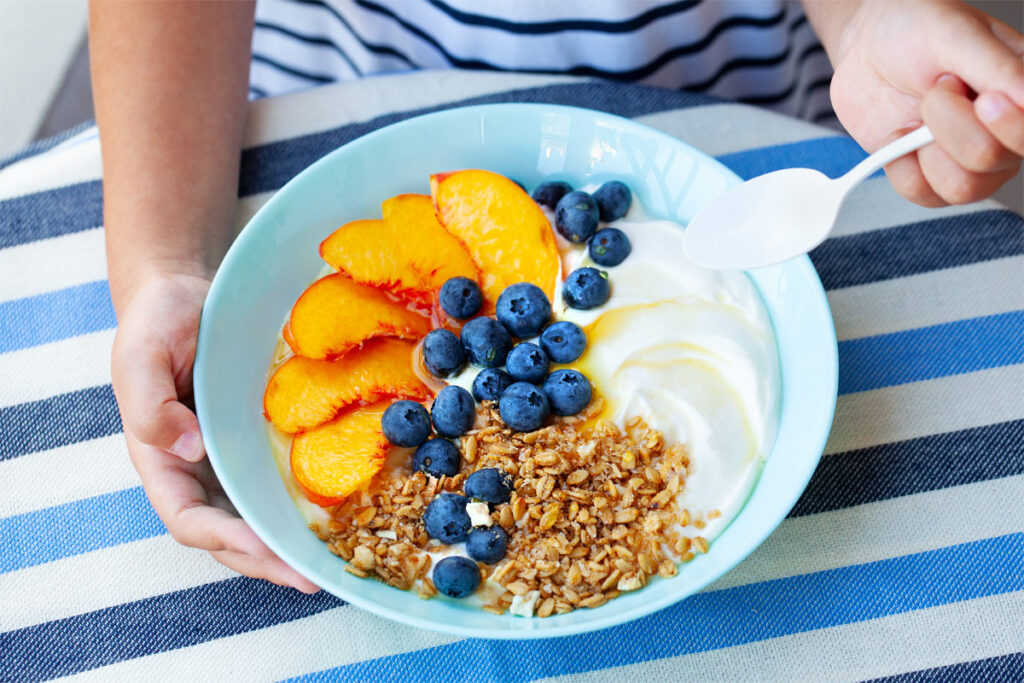 Haferflocken mit verschiedenen Obst in einer blauen Schüssel für Kinder.