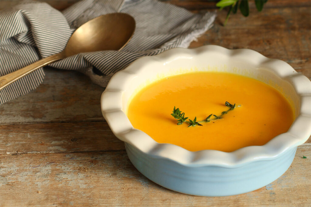Ein Weißer Teller mit Kürbissuppe mit Kartoffeln.