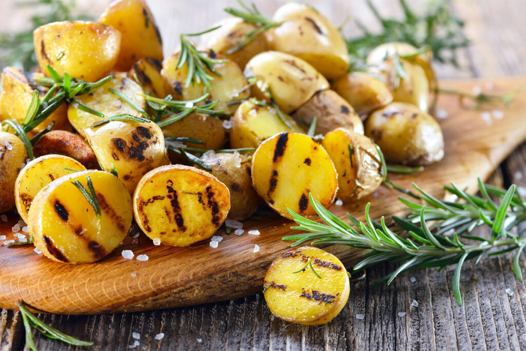 ein Holzbrett mit fertiggegrillten Kartoffeln