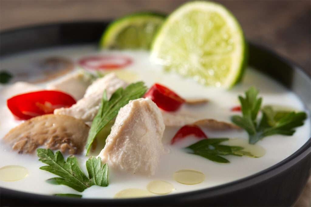 Eine schwarze Schüssel mit Tom Kha Gai gefüllt.