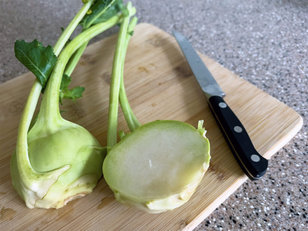 Kohlrabi in zwei Hälften geschnitten liegt auf einem Holzbrett.